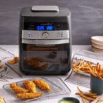 Pampered Chef Deluxe Air Fryer mit knusprigen Pommes und Hähnchenstreifen auf dem Tisch