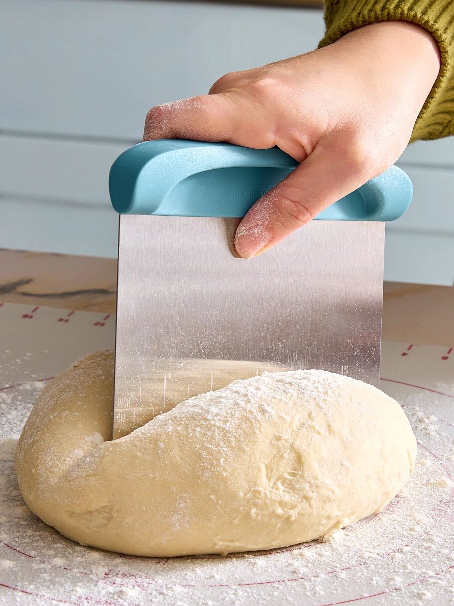 Pampered Chef® Teigschneider mit Edelstahlklinge teilt Hefeteig auf bemehlter Teigunterlage